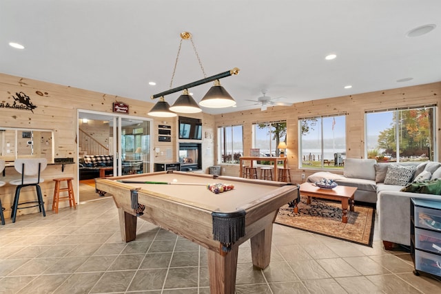 rec room with a wealth of natural light, ceiling fan, wood walls, and billiards