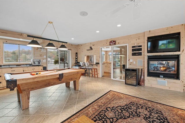 recreation room with ceiling fan, a multi sided fireplace, wine cooler, wooden walls, and pool table