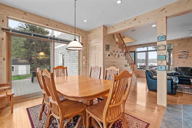 dining space with wood walls, light hardwood / wood-style flooring, and a healthy amount of sunlight