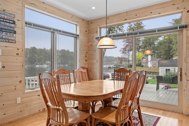 dining space with a water view, a healthy amount of sunlight, and light wood-type flooring