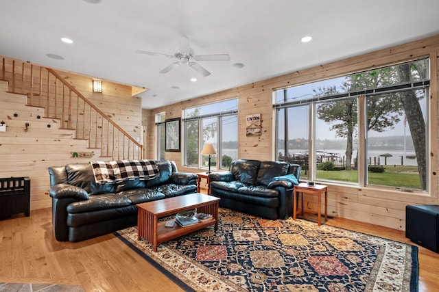 living room with a healthy amount of sunlight, light hardwood / wood-style floors, and wooden walls