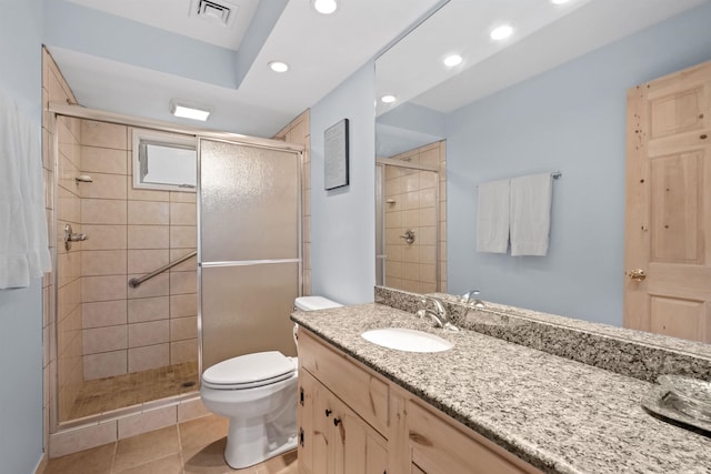 bathroom with tile patterned flooring, vanity, an enclosed shower, and toilet