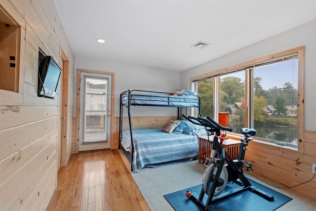 bedroom with light wood-type flooring and wooden walls