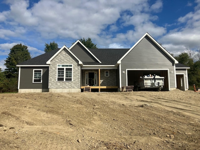 view of front of house with a garage, stone siding, a shingled roof, and covered porch