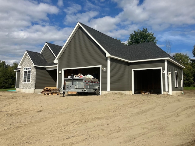 view of front of home with an attached garage, driveway, and roof with shingles