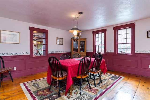 dining room with wood-type flooring and a textured ceiling