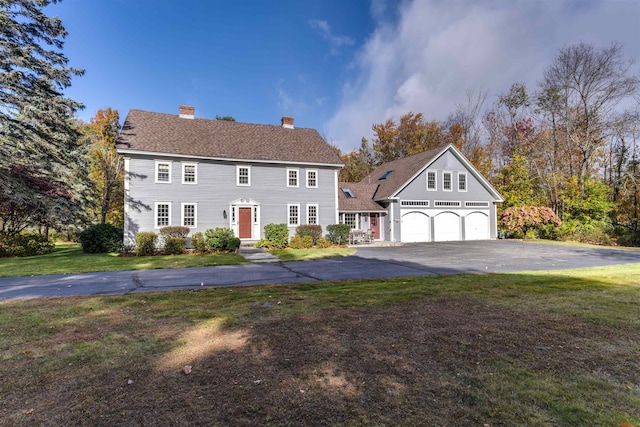 colonial house featuring a garage and a front lawn