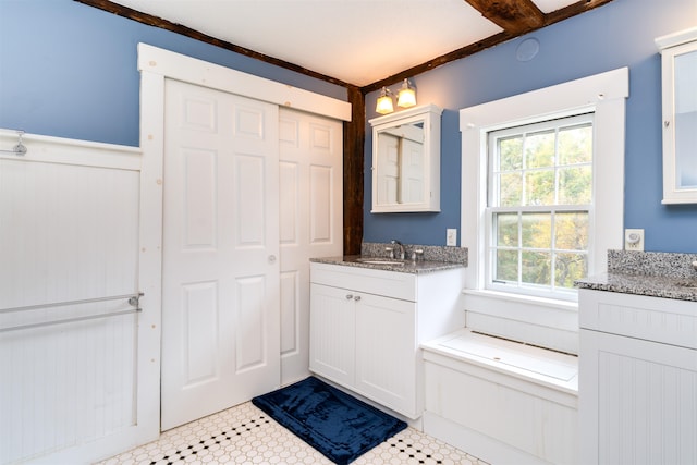 bathroom featuring beamed ceiling, tile patterned floors, and vanity