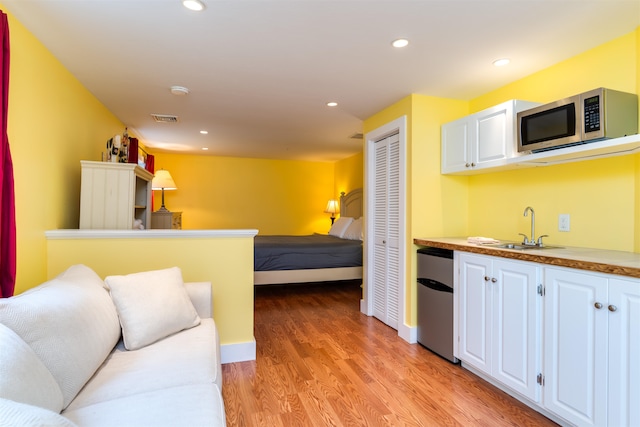 kitchen featuring white cabinets, appliances with stainless steel finishes, sink, and light wood-type flooring