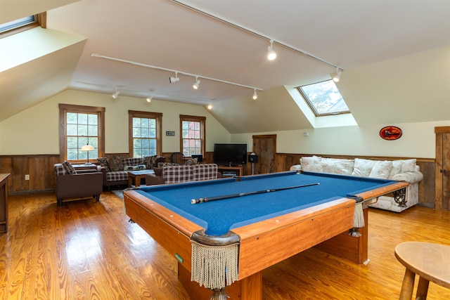 recreation room featuring track lighting, hardwood / wood-style flooring, lofted ceiling, and wood walls