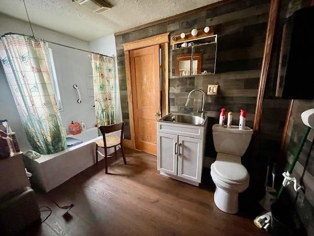 full bathroom featuring toilet, shower / tub combo, hardwood / wood-style floors, vanity, and a textured ceiling