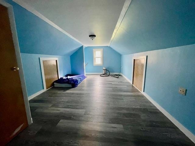 additional living space featuring dark wood-type flooring and vaulted ceiling