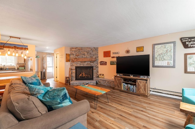 living room featuring baseboard heating, a stone fireplace, and wood-type flooring