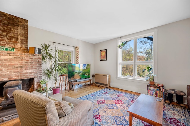 living room featuring heating unit, hardwood / wood-style floors, a healthy amount of sunlight, and a brick fireplace