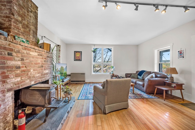 living room with light hardwood / wood-style floors, a wood stove, and rail lighting