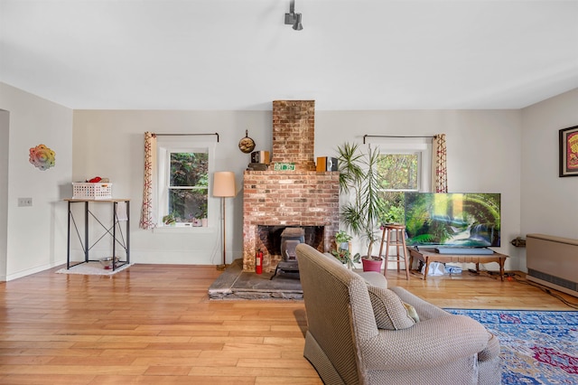 living room with heating unit, light hardwood / wood-style flooring, and a brick fireplace