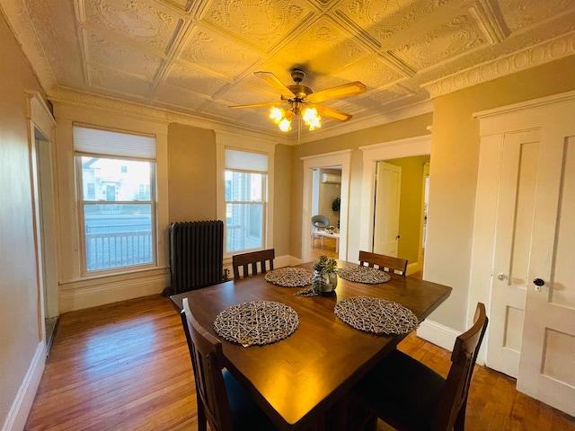 dining space with wood-type flooring, radiator heating unit, and ceiling fan