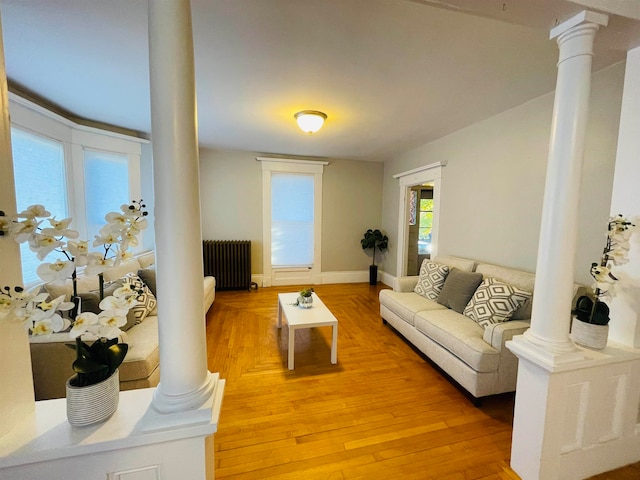 living room with ornate columns, radiator heating unit, and hardwood / wood-style flooring