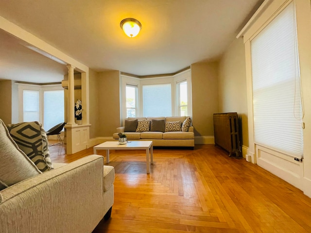 living room with radiator, decorative columns, and wood-type flooring