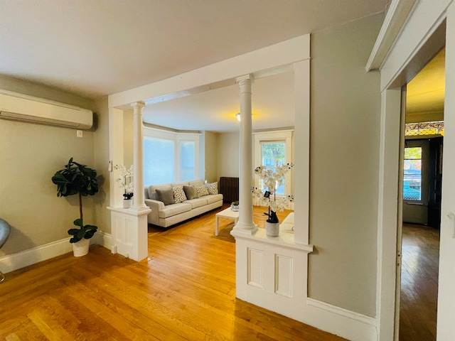 living room featuring light hardwood / wood-style floors, a wall mounted AC, and a healthy amount of sunlight