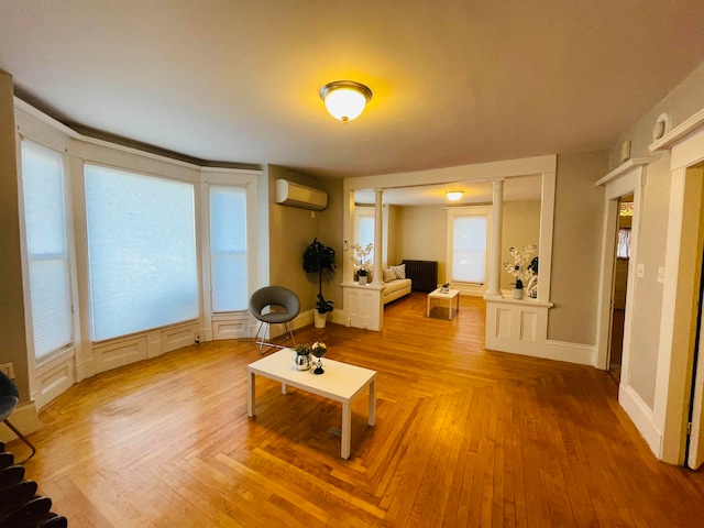 living area featuring a healthy amount of sunlight, a wall mounted air conditioner, and hardwood / wood-style floors