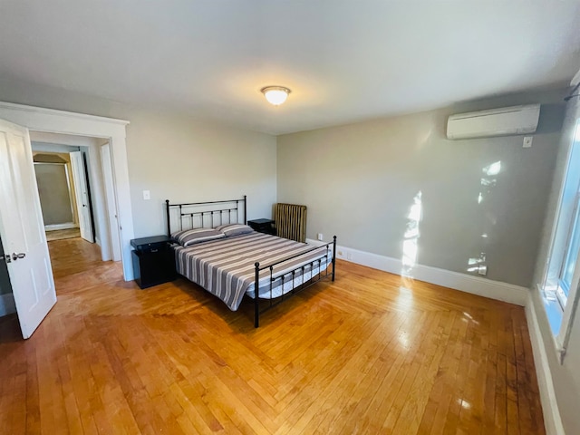 bedroom featuring a wall mounted air conditioner and hardwood / wood-style flooring