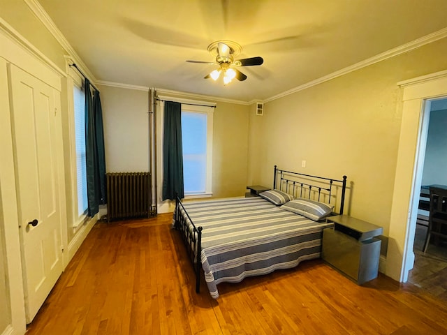 bedroom with ornamental molding, radiator heating unit, wood-type flooring, and ceiling fan