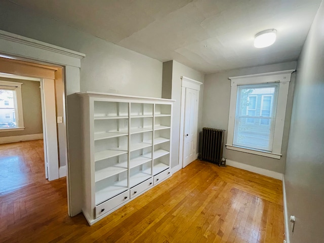 corridor with hardwood / wood-style floors, radiator, and a wealth of natural light