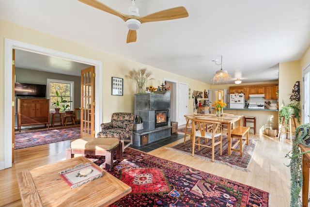 living room featuring a tiled fireplace, light hardwood / wood-style floors, and ceiling fan