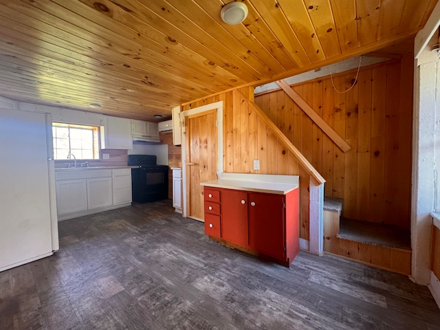 kitchen with black range oven, dark wood-type flooring, wooden ceiling, wood walls, and white cabinets