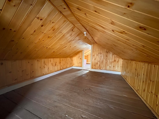 additional living space featuring dark hardwood / wood-style floors, vaulted ceiling, and wooden walls