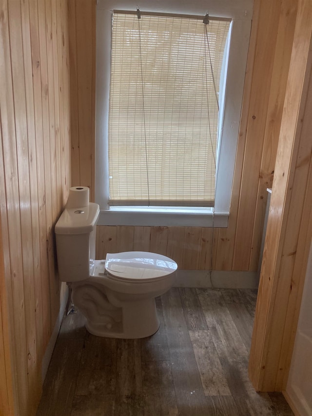 bathroom with hardwood / wood-style floors, wood walls, and toilet