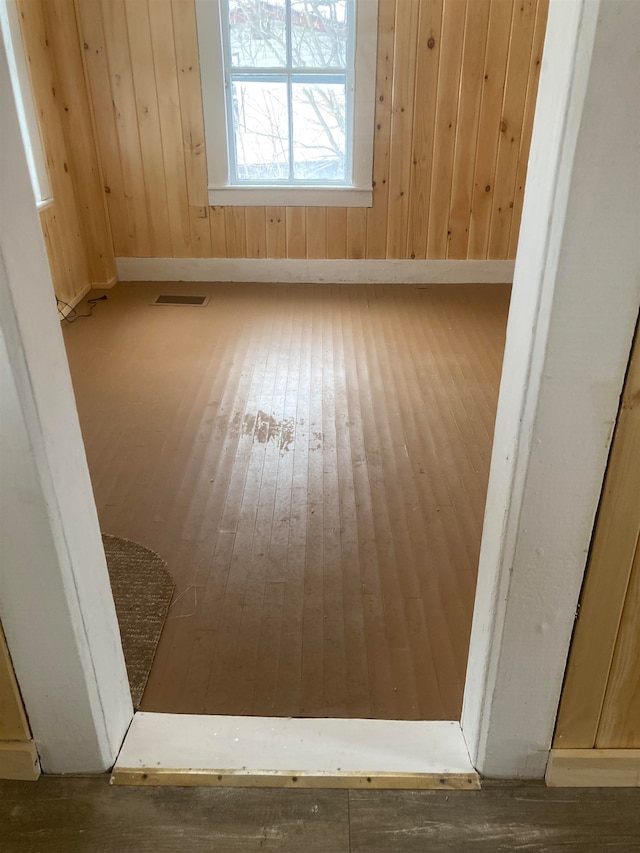 unfurnished room featuring wood walls and wood-type flooring