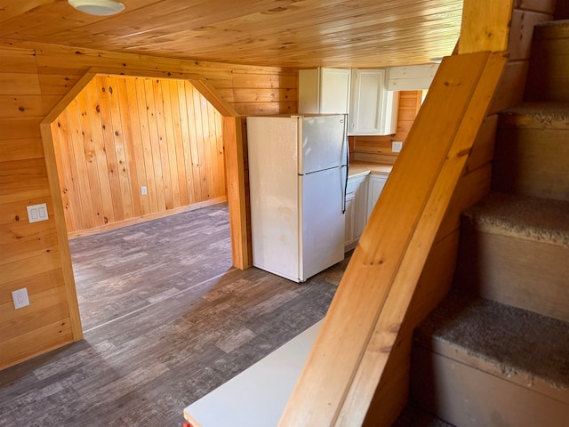 kitchen with dark hardwood / wood-style flooring, wood ceiling, wooden walls, white refrigerator, and white cabinetry