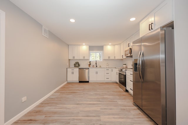 kitchen featuring appliances with stainless steel finishes, light hardwood / wood-style flooring, and white cabinetry