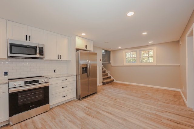 kitchen featuring decorative backsplash, white cabinetry, light stone countertops, light hardwood / wood-style flooring, and stainless steel appliances