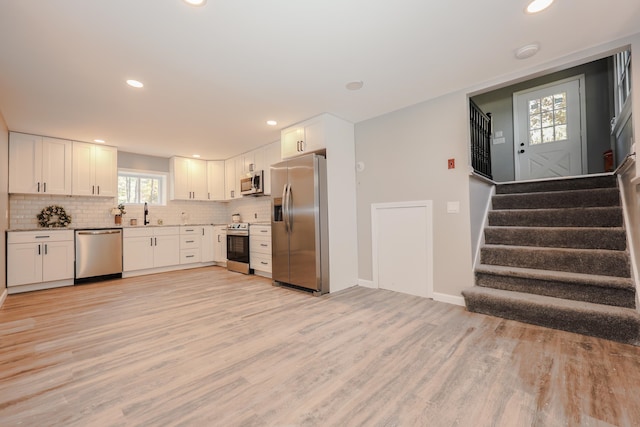 kitchen with light hardwood / wood-style flooring, sink, white cabinetry, appliances with stainless steel finishes, and tasteful backsplash