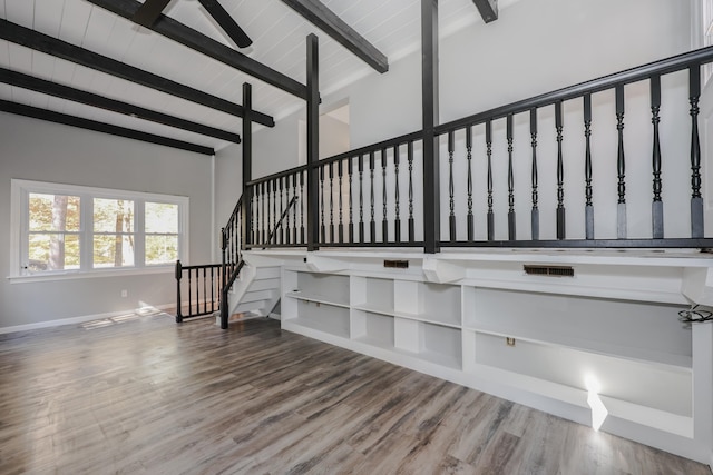 stairway featuring high vaulted ceiling, beamed ceiling, and hardwood / wood-style floors