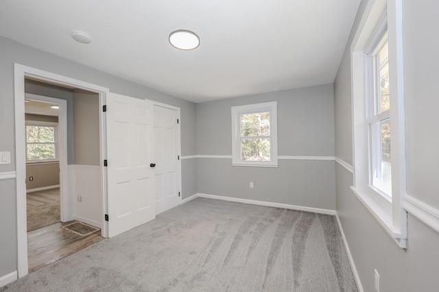 unfurnished bedroom with light carpet, multiple windows, and a closet