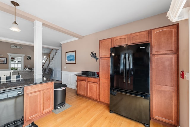 kitchen with light wood-type flooring, dark stone counters, black appliances, ornate columns, and decorative light fixtures