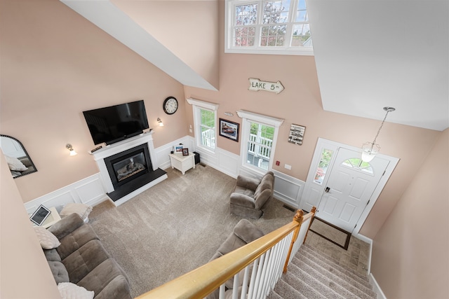 carpeted living room featuring a towering ceiling