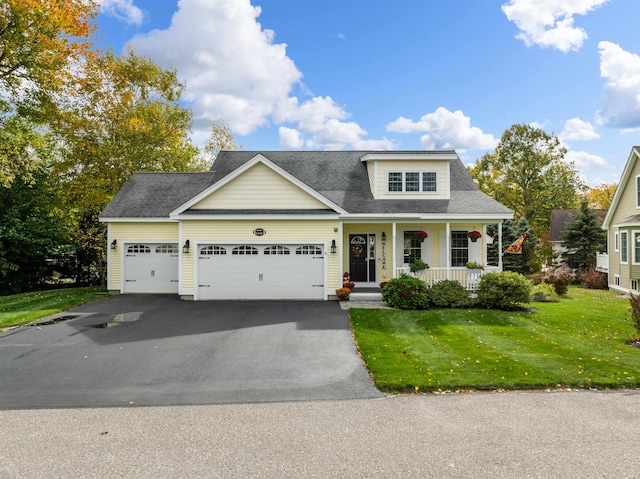 view of front of house with covered porch, a garage, and a front lawn