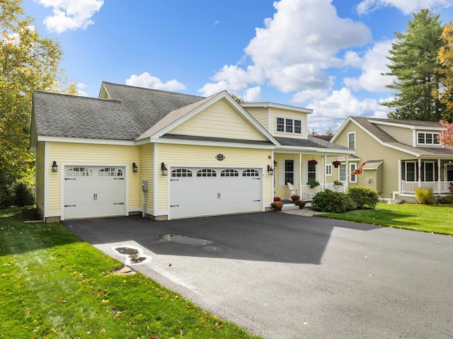 view of property featuring a garage, a front lawn, and a porch