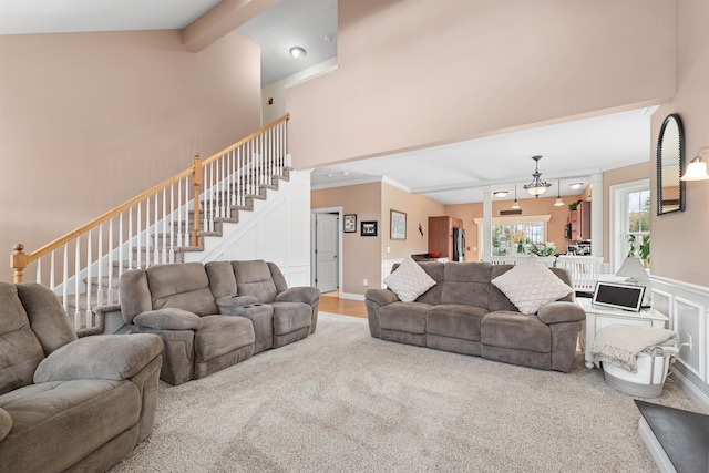 living room with ornamental molding, carpet floors, and high vaulted ceiling