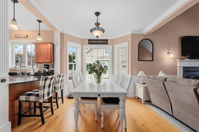 dining space featuring sink, ornamental molding, and light hardwood / wood-style flooring