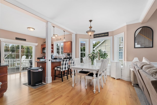 dining room featuring a wealth of natural light, ornamental molding, light hardwood / wood-style flooring, and ornate columns