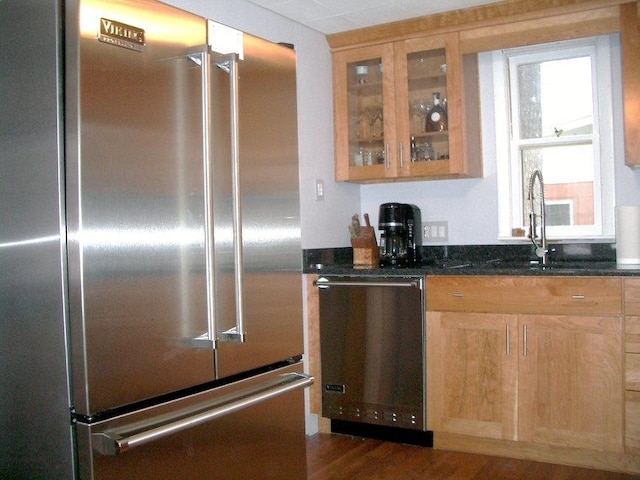 kitchen featuring dark stone countertops, stainless steel appliances, dark wood-type flooring, and sink