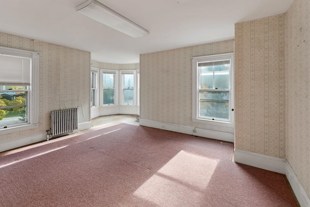 unfurnished living room with carpet, radiator heating unit, and plenty of natural light