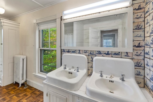 bathroom featuring radiator, parquet flooring, crown molding, and vanity