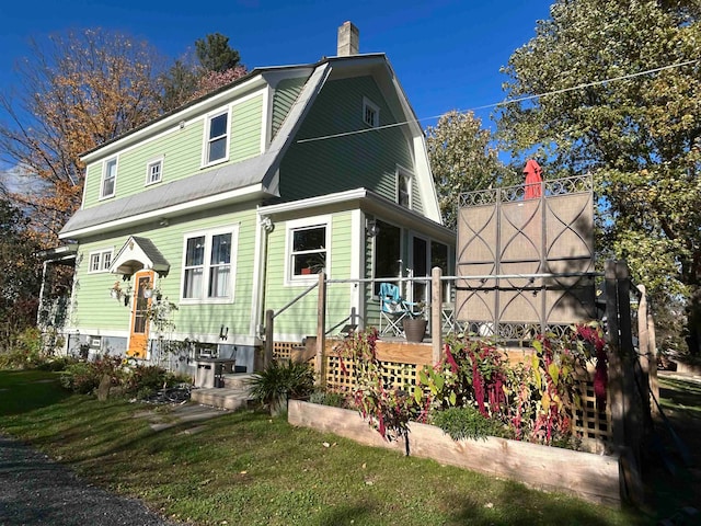 view of front of house featuring a wooden deck, a sunroom, and a front yard